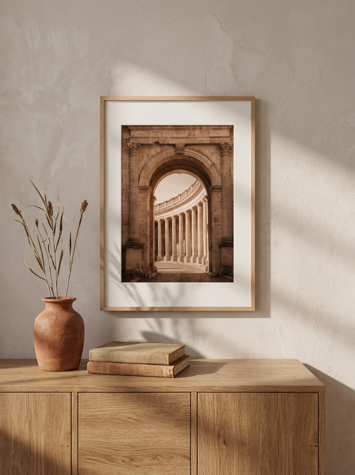 Stampa Arco Romano appesa sopra una credenza bassa in rovere, con un vaso in terracotta con rami secchi e due libri rilegati in lino